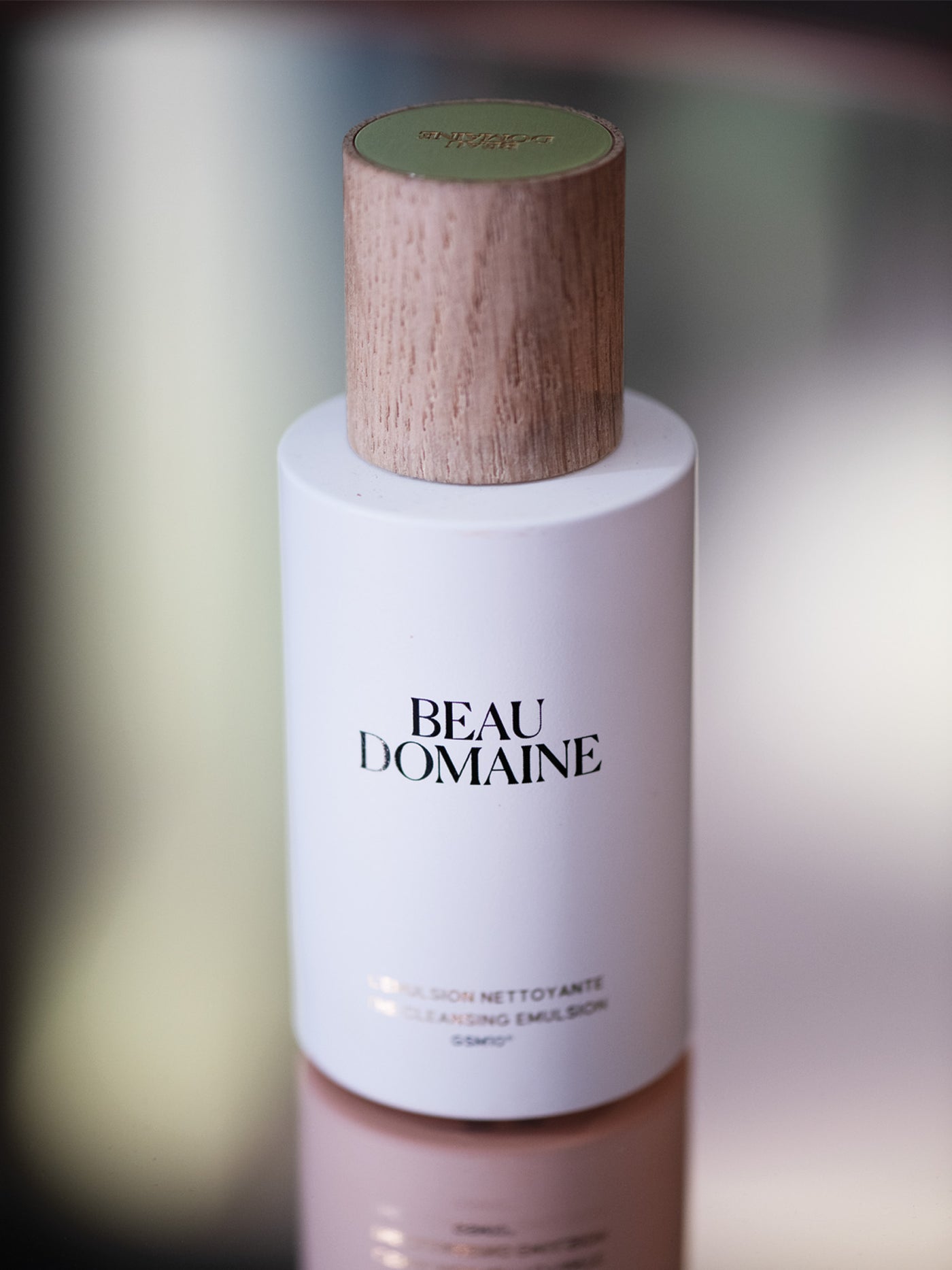 Beau Domaine huidverzorgingsfles met houten dop op een onscherpe achtergrond.